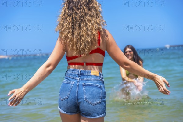 Two young women are enjoying their summer vacation, playing and splashing in the refreshing ocean