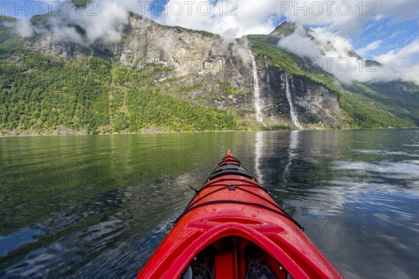 Kayak trip on the Geirangerfjord with waterfall The Seven Sisters, tip of a red kayak in the fjord,