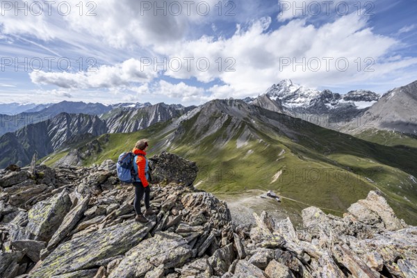 Mountaineer on the summit of Kastenegg, view of picturesque mountain landscape with snow-covered