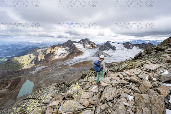 Mountaineer with helmet on a rocky hiking trail, in high mountain landscape, view of blue glacial