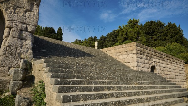 Stone staircase next to old walls, surrounded by nature and trees, open staircase to the second