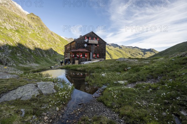 Mountain hut Elberfelderhütte with small lake and cotton grass, in the morning light, in the upper