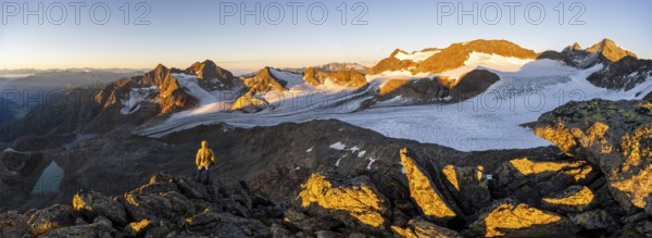 Mountaineers in front of a picturesque high mountain landscape at sunrise with alpenglow, blue