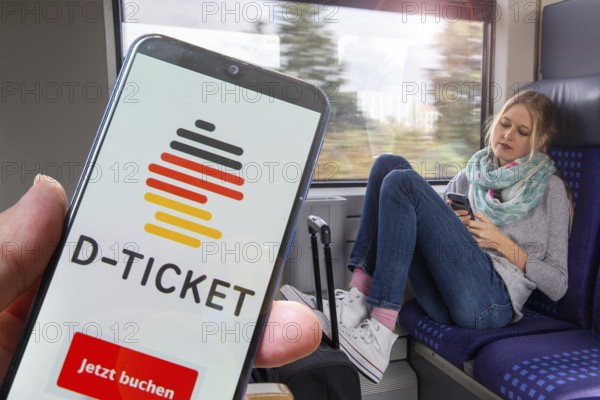 (Photomontage) Logo of the Deutschlandticket on the smartphone, in the background a young woman on