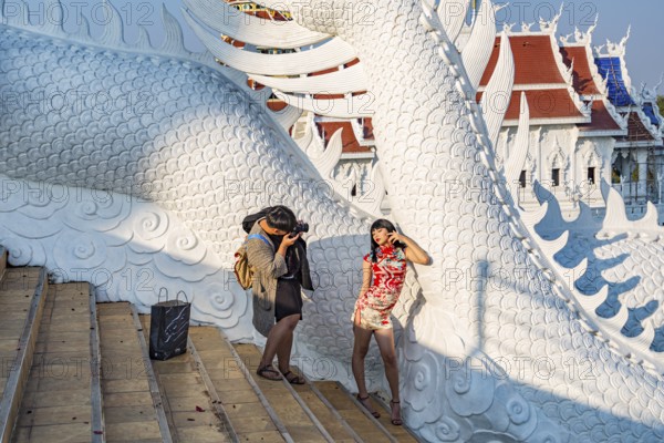 Photographer photographing young Thai woman on the steps of the Guan Yin (Goddess of Mercy) statue