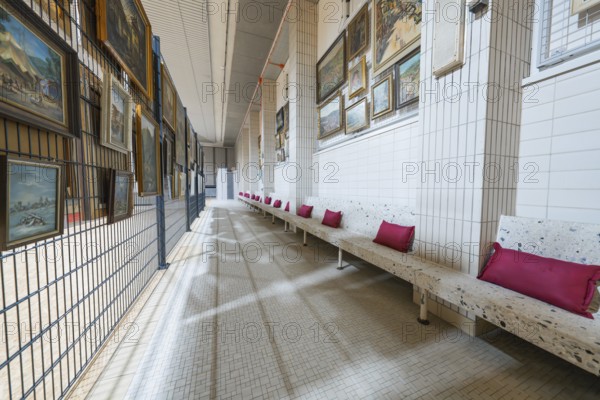 Long corridor with paintings on the walls and upholstered benches, historical art exhibition in the