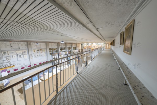 A wide corridor in a gallery with works of art on the walls and modern architectural design,