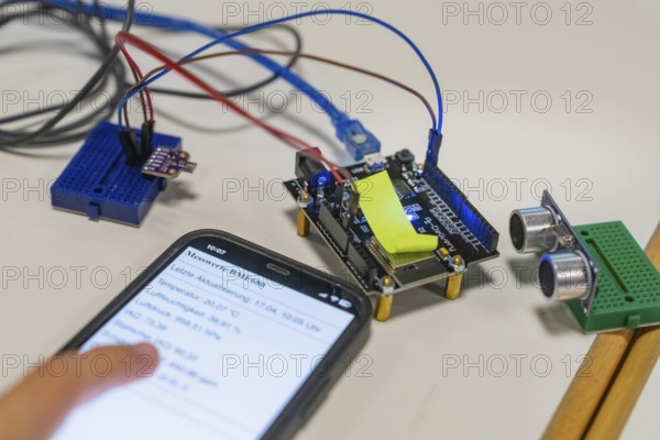 Smartphone with displayed data next to an electronic setup on a table, Youth Research Centre