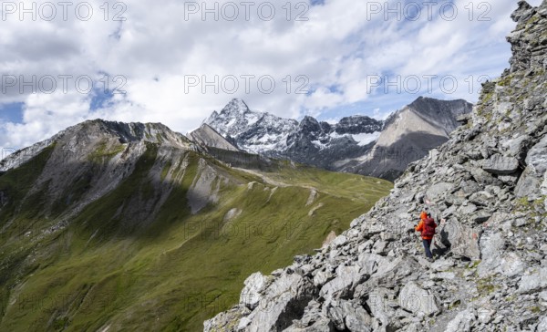 Mountaineer on steep rocky hiking trail, descent from the summit of Kastenegg, view of picturesque