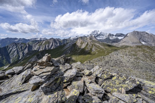 Cairn on the summit of Kastenegg, view of picturesque mountain landscape with snow-covered summit