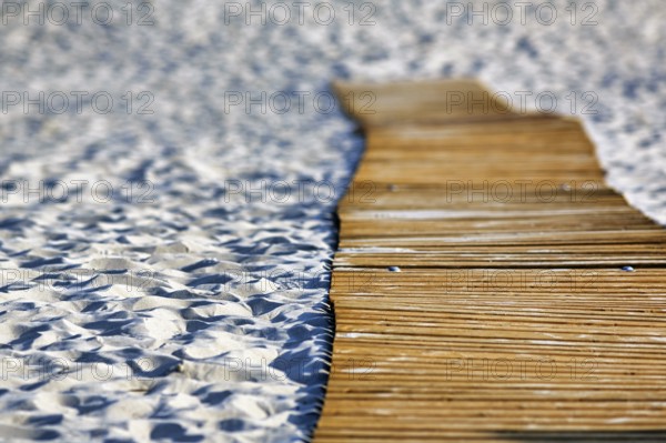 Empty wooden path on the sandy beach, wooden mat in the sand, barrier-free access,