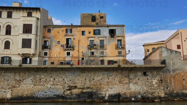 Houses with colourful facades and balconies along a stone seawall, boat trip around the island of