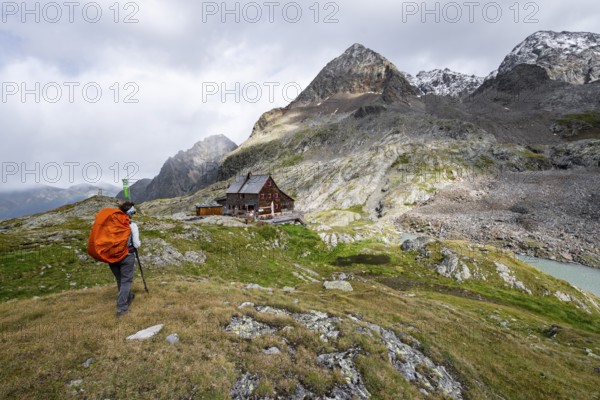Mountaineer in front of mountain hut Adolf-Nossberger-Hütte, mountain landscape with rocky mountain
