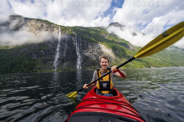 Kayak trip on the Geirangerfjord at the waterfall The Seven Sisters, Young man paddling in a kayak,