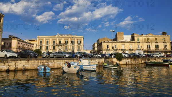 Boats on a waterfront in a town in the warm light and under a blue sky, boat trip around the island
