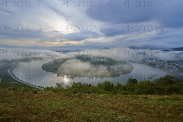 Fog-covered river landscape with rolling hills and overcast sky in calm light, summer, Rhine bend