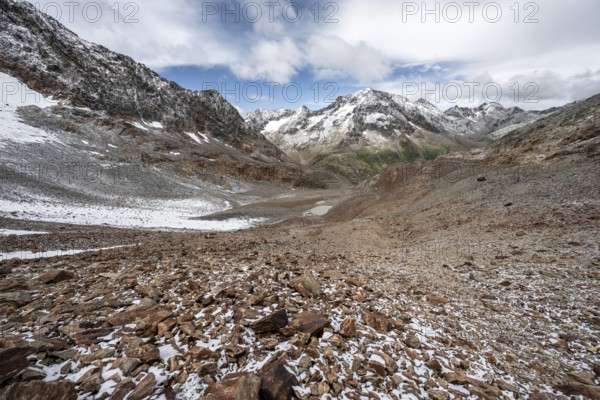 View of steep rocky mountain landscape with fresh snow in summer, descent from the Hornscharte, on