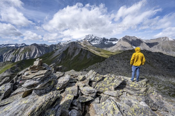Mountaineer on the summit of Kastenegg, view of picturesque mountain landscape with snow-covered