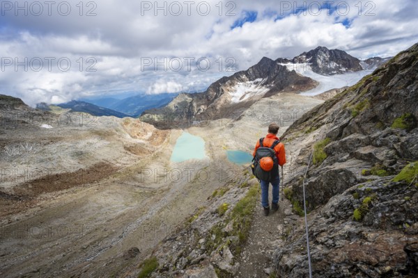 Mountaineer with helmet in high mountain landscape, view of blue glacial lakes, mountain peaks
