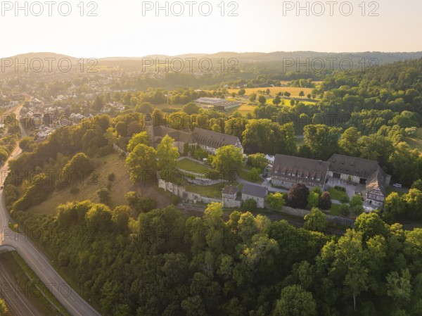 Wide aerial view of a monastery complex in a wooded landscape at sunset, event and wedding location