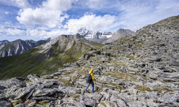 Mountaineer in boulder terrain, at the summit of Kastenegg, view of picturesque mountain landscape