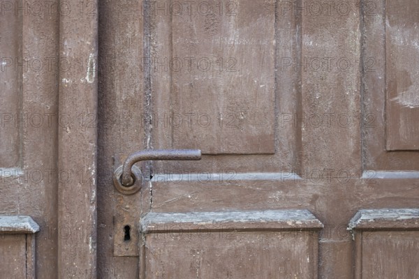 Weathered brown wooden door with rusty door handle and visible texture, Bad Bergzabern, Southern