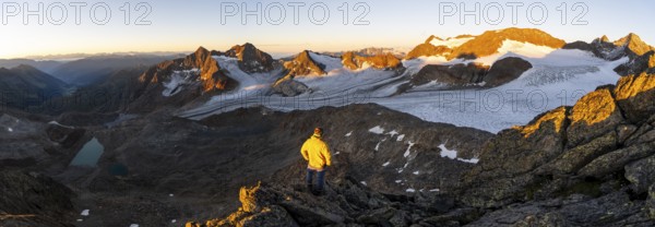 Mountaineers in front of a picturesque high mountain landscape at sunrise with alpenglow, blue