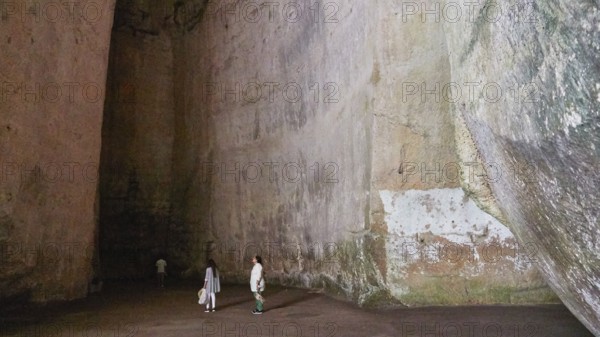Cave Ear of Dionysus, Large rock cave with several people exploring the dark surroundings, Neapolis