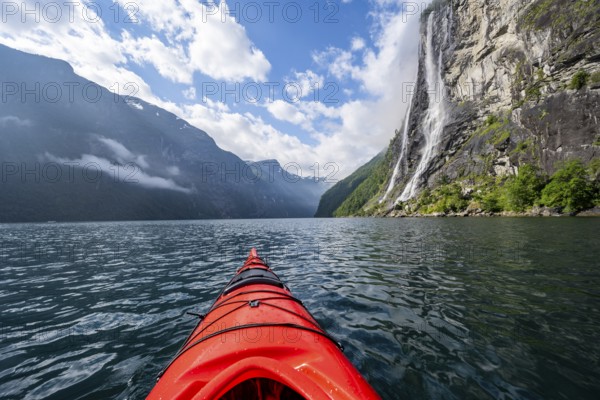 Kayak trip on the Geirangerfjord at the waterfall The Seven Sisters, tip of a red kayak in the