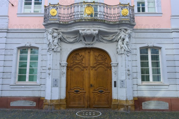 Magnificent wooden door of a pink façade with classical sculptures and decorative details in