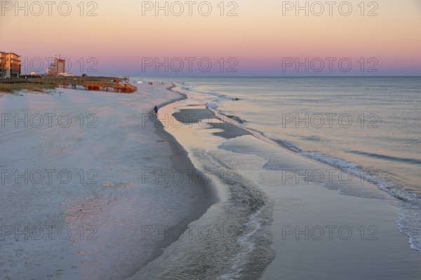 Woman and child walking along the Gulf of Mexico beach as the sun rises over the Gulf of Mexico at