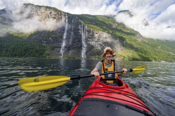Kayak trip on the Geirangerfjord at the waterfall The Seven Sisters, Young man paddling in a kayak,