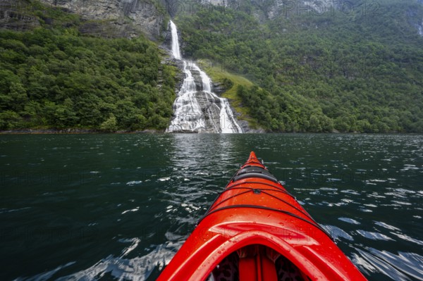 Kayak trip on the Geirangerfjord at the Freier waterfall, tip of a red kayak in the fjord,