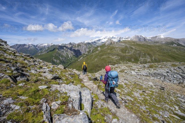 Mountaineers on a hiking trail, view of picturesque mountain landscape with snow-covered summit of