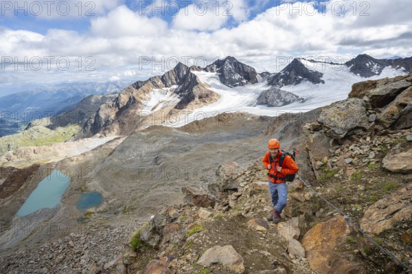 Mountaineer with helmet in high mountain landscape, view of blue glacier lakes, mountain peaks