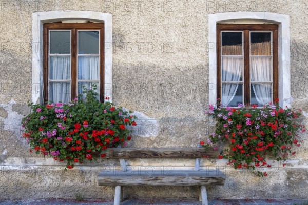 Two windows with flower boxes and wooden bench on a charming stone wall, Umrathshausen, Bavaria,