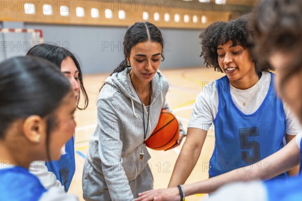 Female basketball coach motivating and inspiring her team during a time out, holding the ball and