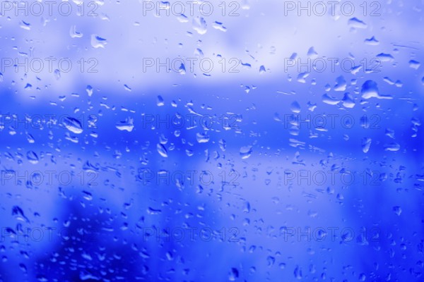 Raindrops on a window, illustrating gray and rainy weather during the day. Black and white