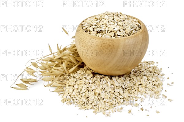 Oat flakes in a wooden bowl, oat stalks, oat flakes scattered on the table, against a white