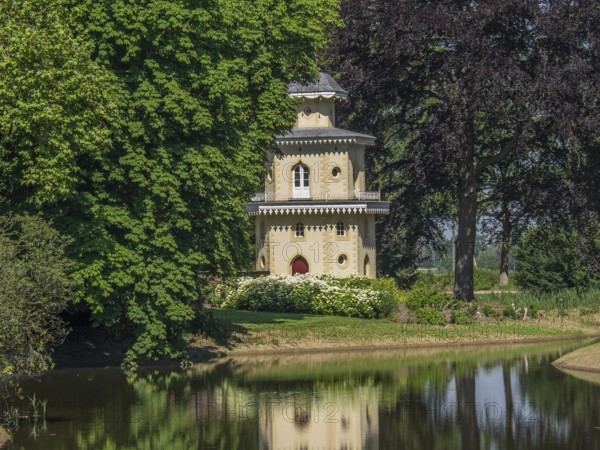 Historic turret flanked by trees, reflected in the neighbouring water, ulft, gelderland,