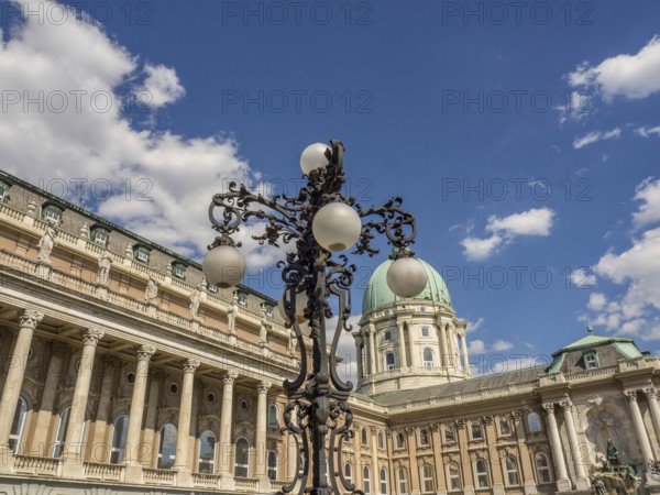 Historic castle with impressive dome and ornately forged lantern under a blue sky with white