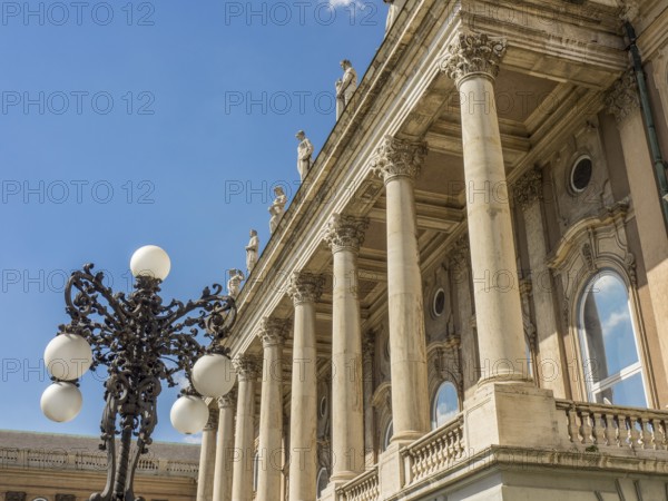 A building with classical columns, decorated with an ornate street lamp and blue sky in the