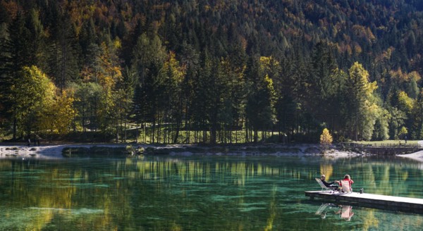 Kranjska Gora, Slovenia, 18 October, 2021: tourists enjoy relaxing on the wooden dock at Lake Jasna