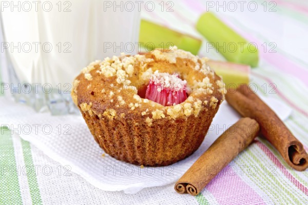 Cupcake with rhubarb, cinnamon on a white paper napkin, rhubarb, milk in a glass on a background of