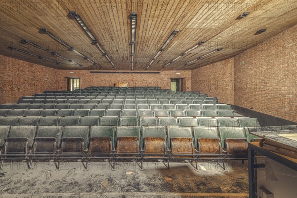 Dusty, empty lecture theatre with green rows of seats and visible bricks, Institute of Molecular