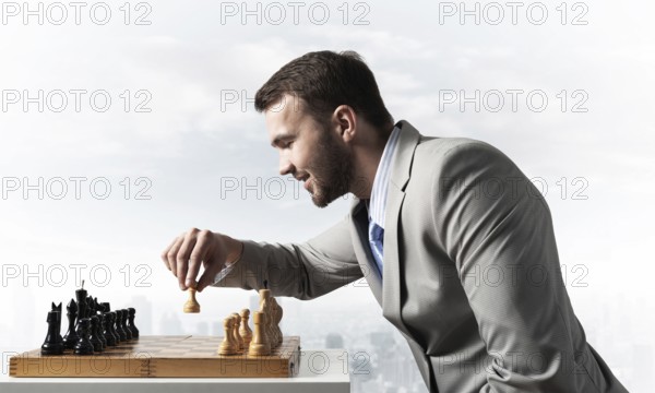 Concentrated businessman playing chess game. Successful management and leadership concept.