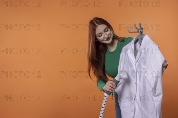 A young woman smiles while preparing a clean white lab coat, showing her care for professional