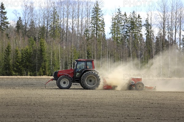 SALO, FINLAND, MAY 7, 2017: Farmer cultivates field with red Valtra tractor and seed drill