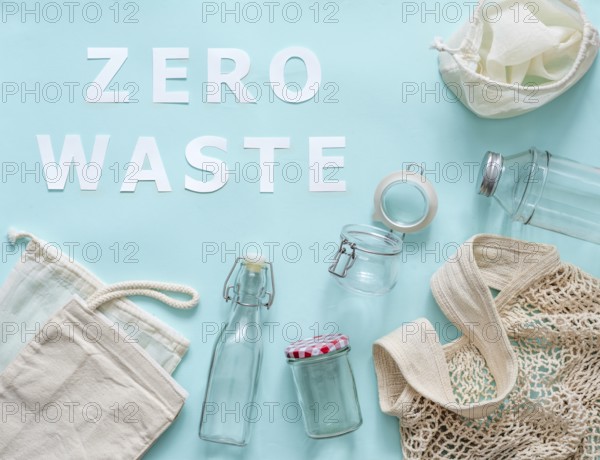 Zero waste concept. Textile eco bags, glass jar and bottle on blue background with Zero Waste white