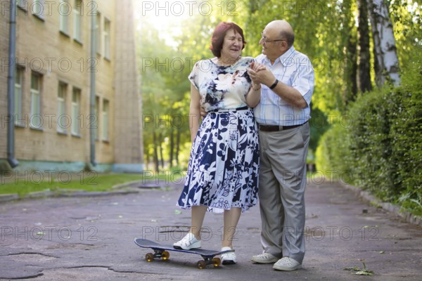 Happy elderly couple with a skateboard. Handsome man and woman seniors. Husband and woman in old